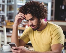 Tensed man using mobile phone in cafeteria